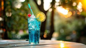 A vibrant blue-green Bullfrog Cocktail in a tall glass with a lemon wheel and cherry garnish.
