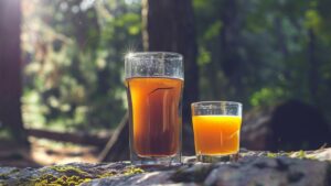 A Cactus Cooler Shot with a shot glass of liquor dropped into a larger glass of energy drink and orange juice.