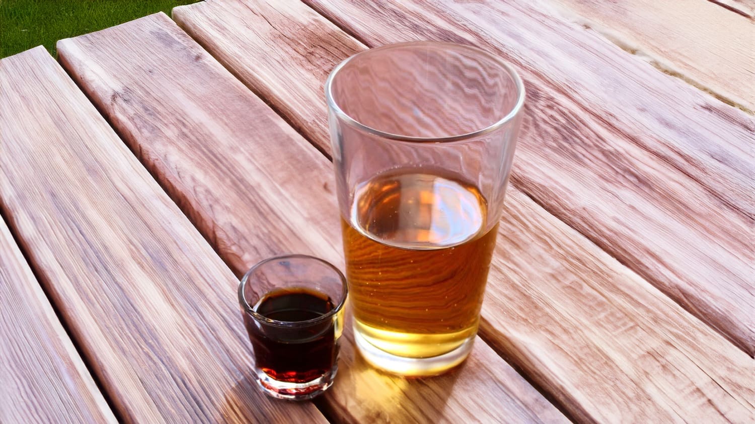 A Jäger Bomb Shot with a shot glass of Jägermeister dropping into a larger glass of an energy drink, creating a splash.