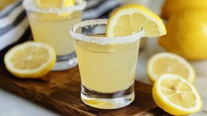 A Lemon Drop Shot in a glass with a sugar rim, and a sugared lemon wedge on the side.