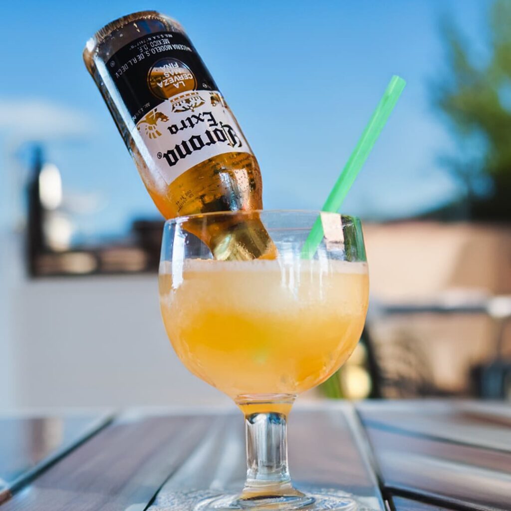 A Mexican Bulldog Cocktail in a large glass with a frozen margarita and an inverted bottle of beer.