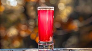 Perfectly layered Wet Pussy Shot with cranberry, cream liqueur, and peach schnapps against a blurred background